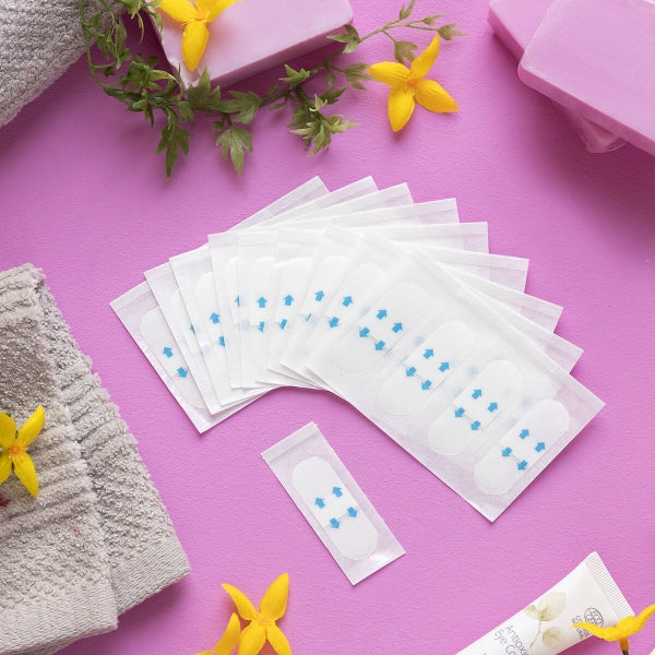 White patches with blue dots on a pink surface with yellow flowers and towels.