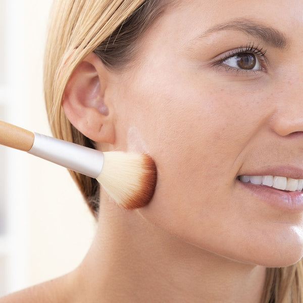Woman having face lifting patch on her face, woman holding makeup brush showing you can wear makeup over patch