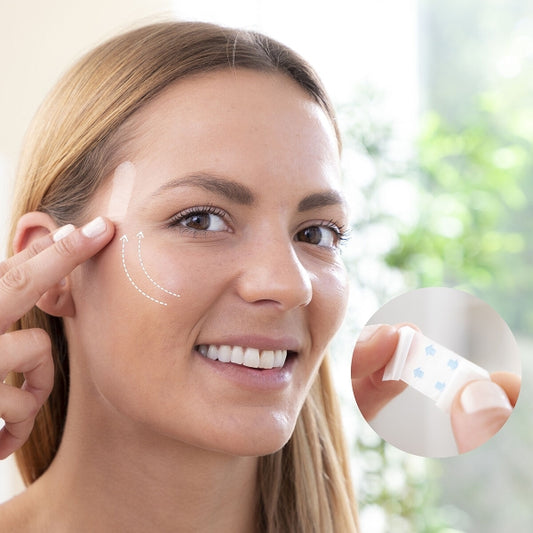 Woman applying skincare product (face lifting patches) to face with a blurred green outdoor background